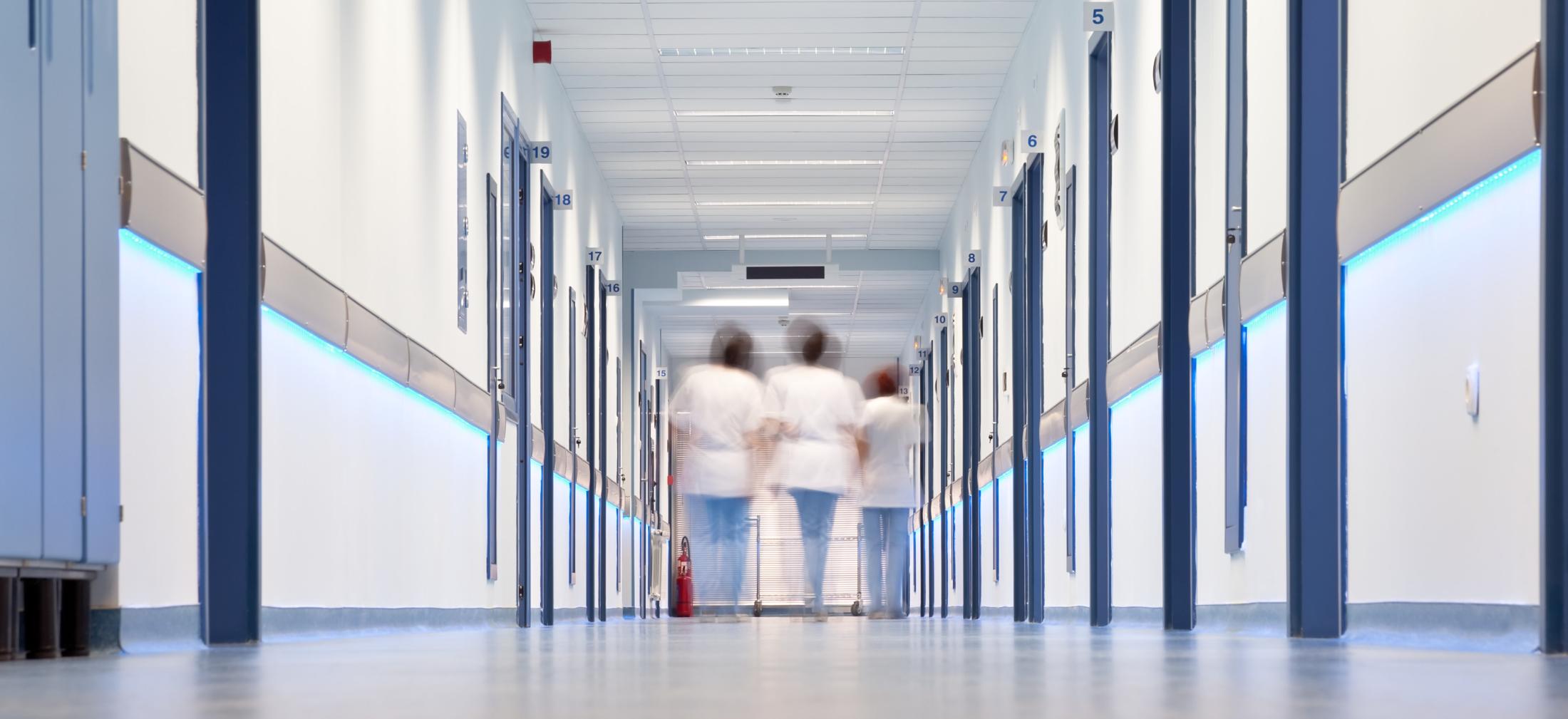 Time-lapsed image of three people walking down the center of a hallway