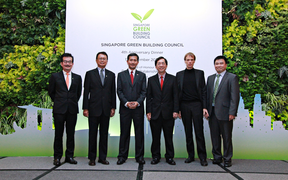 Six people in formal attire standing shoulder to shoulder in front of a sign that says "Singapore Green Building Council"