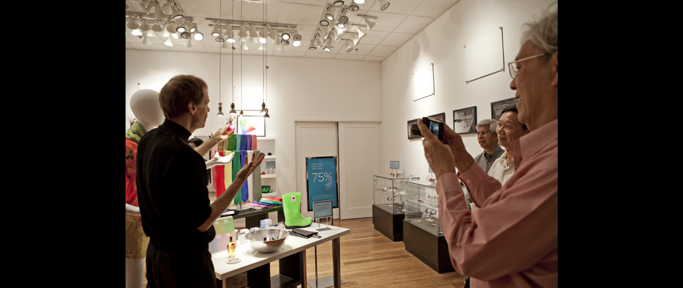 A person standing and talking in front of three other people in a retail store
