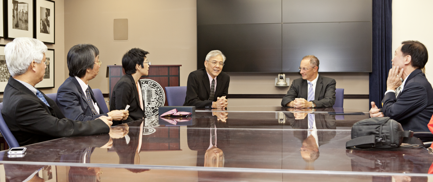Eight people wearing formal attire sitting at a large conference room table