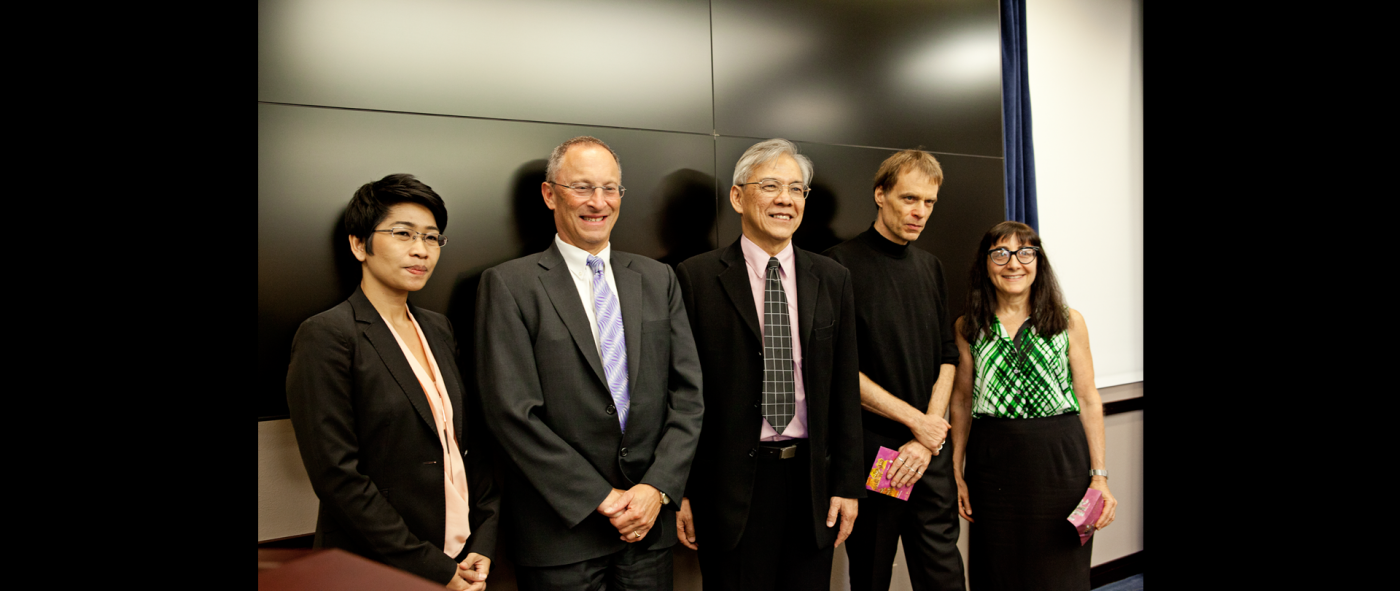 5 people wearing formal attire lined up shoulder to shoulder for a photo
