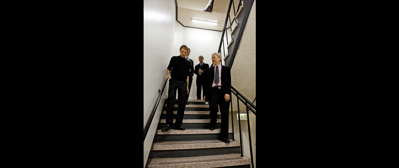 Four people wearing formal attire walking down a stairwell