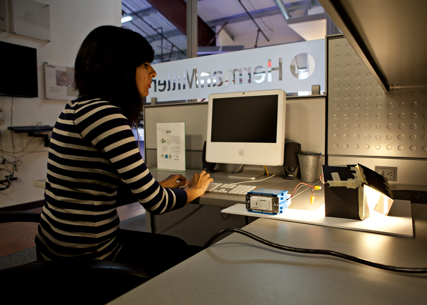 Person sitting at a computer working on building a light fixture