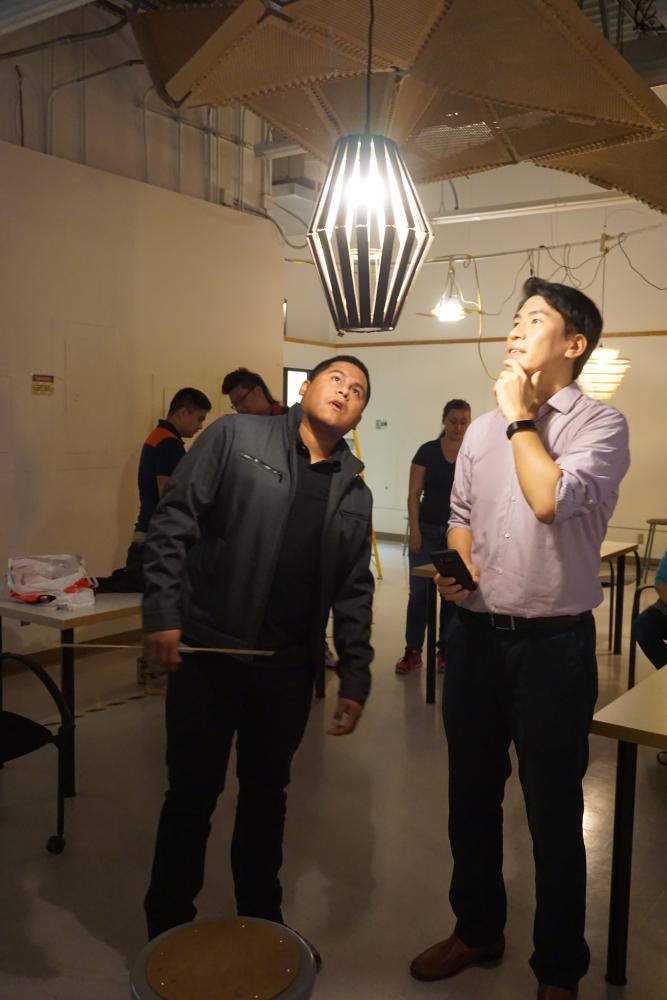 Jae and another person looking at a light fixture hanging from the ceiling