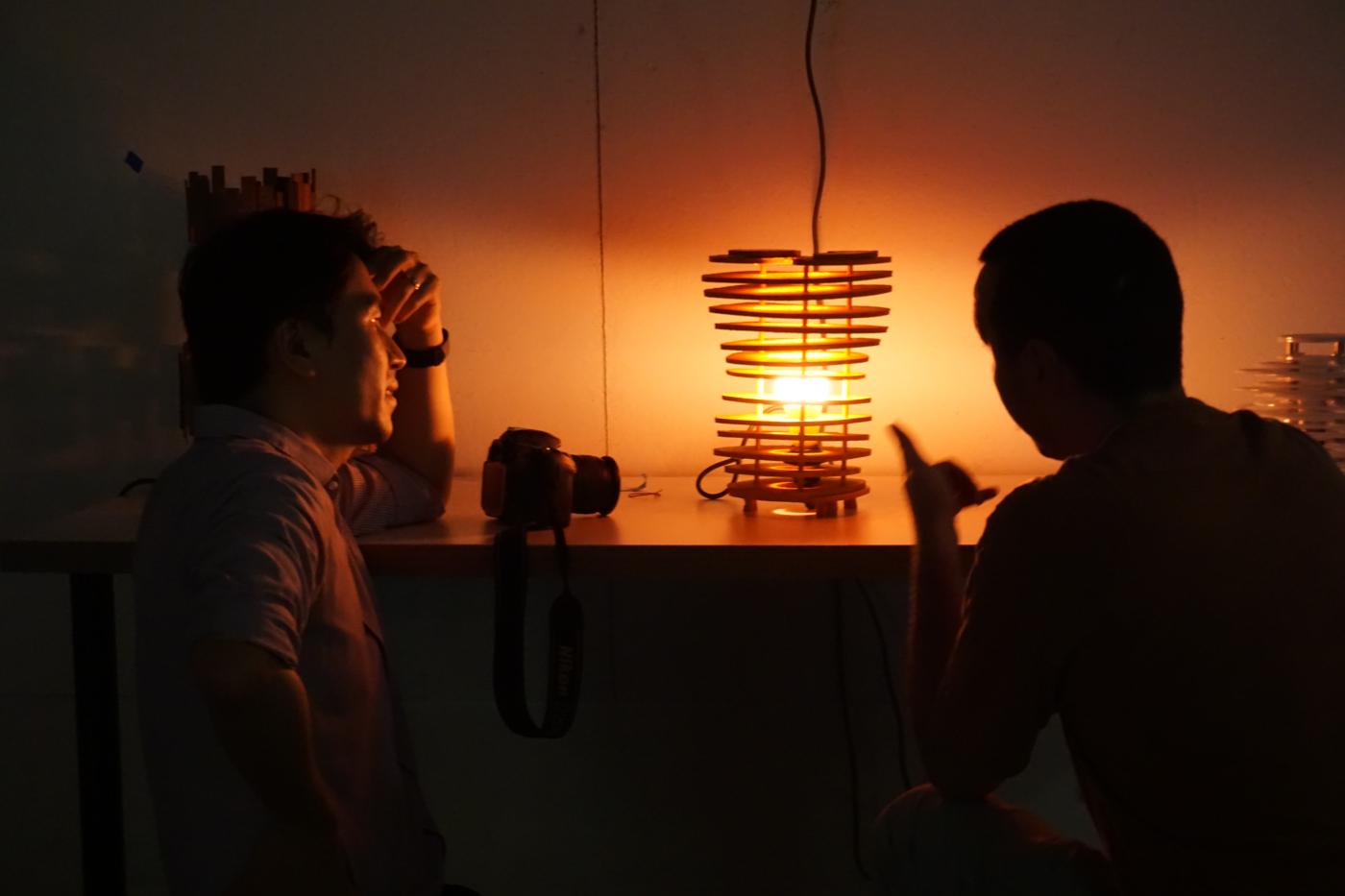 Jae looking at a light source that is emitting warm amber light and has a spiral shape