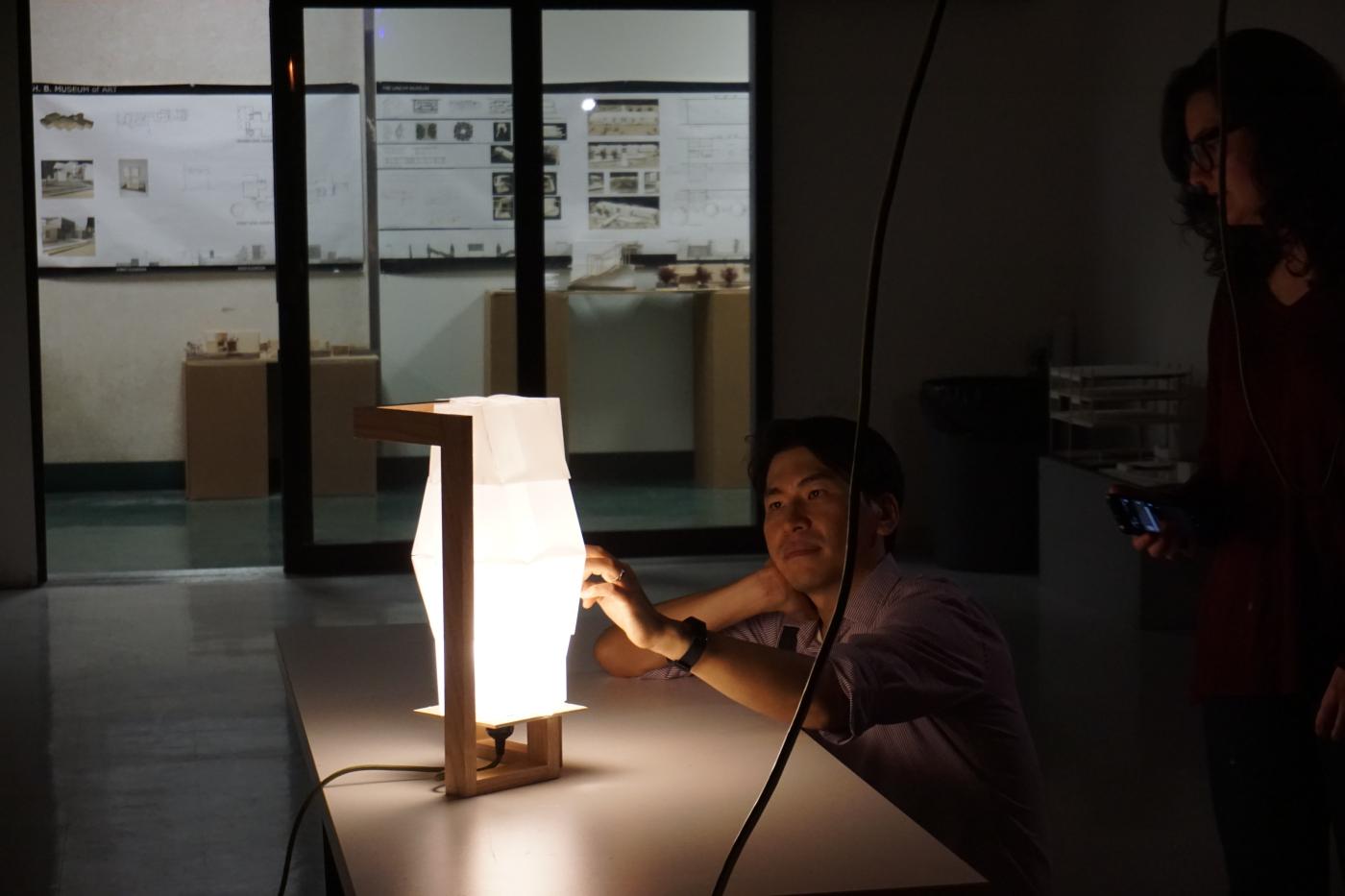 Jae looking at a light source that is sitting on a table
