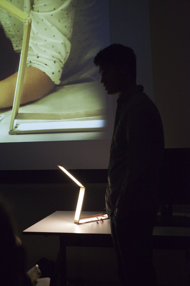 Person standing next to a foldable light fixture with two light panels