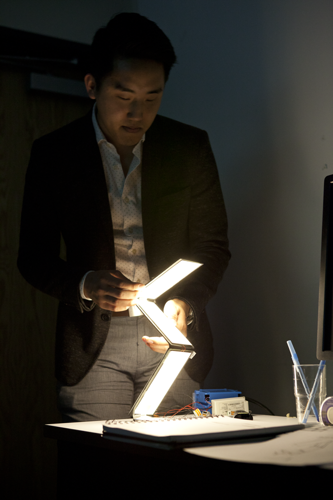 Person holding a foldable light fixture with three panels of light