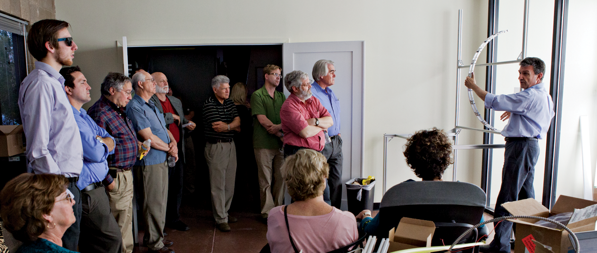 Dr. Papamichael speaking in front of a group of 13 people