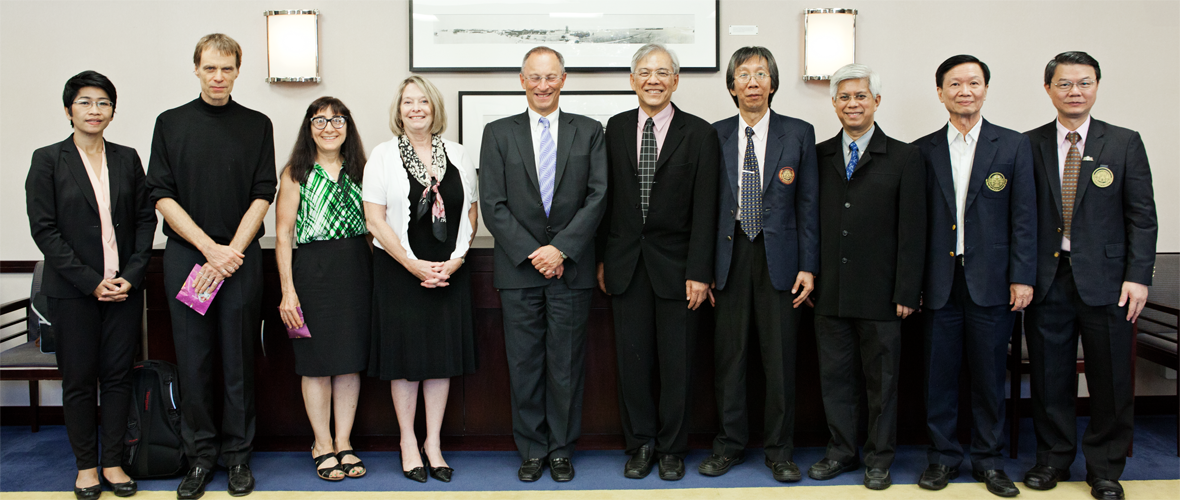 A group of ten people lined up and dressed up in formal attire 