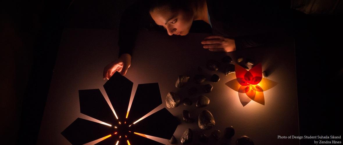 Photo of design student Suhaila Sukand observing a light fixture shaped like a flower 