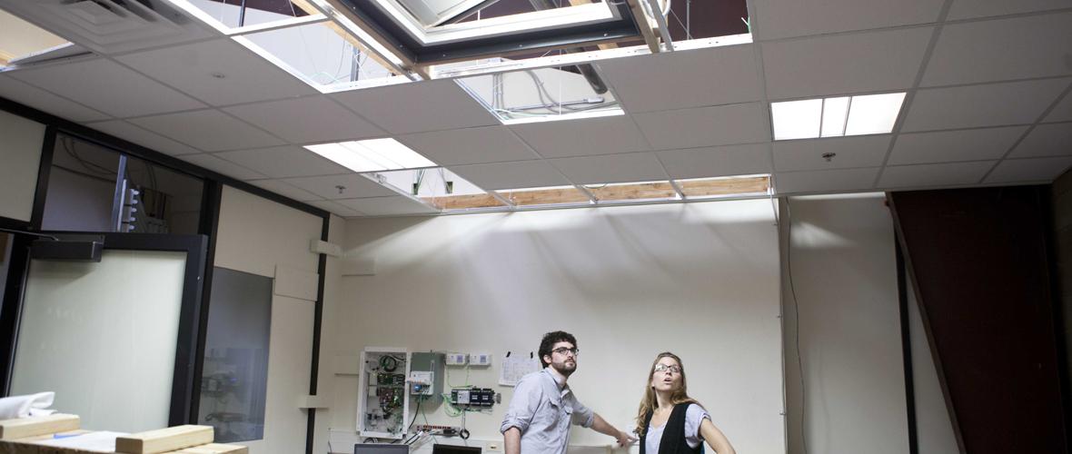 Two people standing in a room looking up at the ceiling