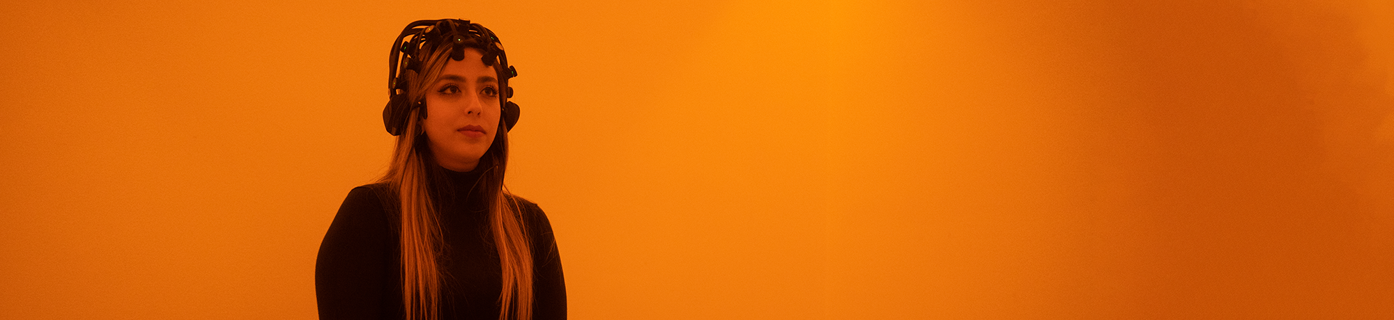 A woman inside a room illuminated with amber lighting