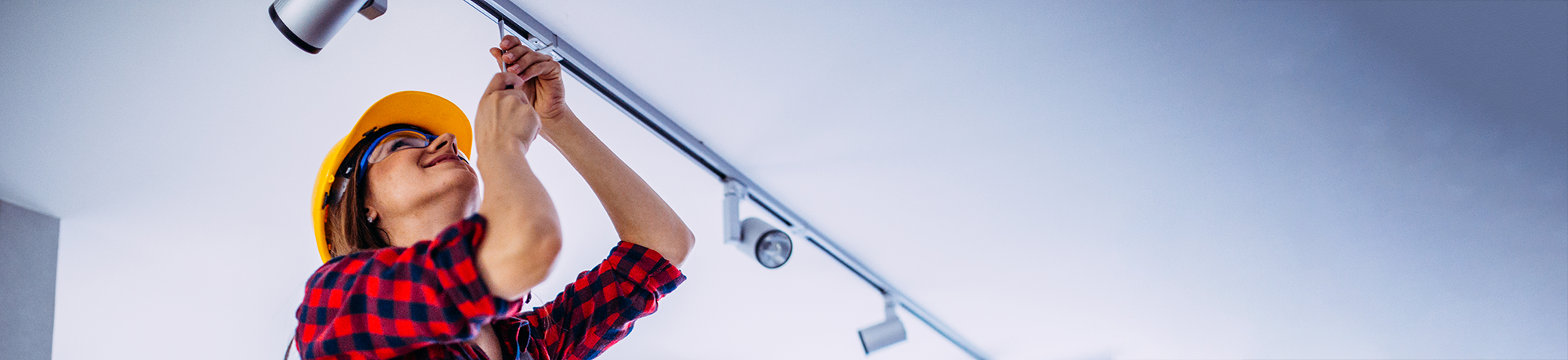 Woman on ladder fixing LED track lighting affixed on a white ceiling