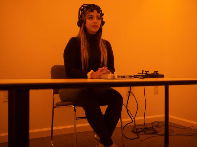 Woman sitting in front of a table inside an orange-lit room