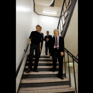 Four people wearing formal attire walking down a stairwell