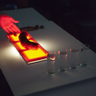 Close up of a red light fixture next to three glasses of water